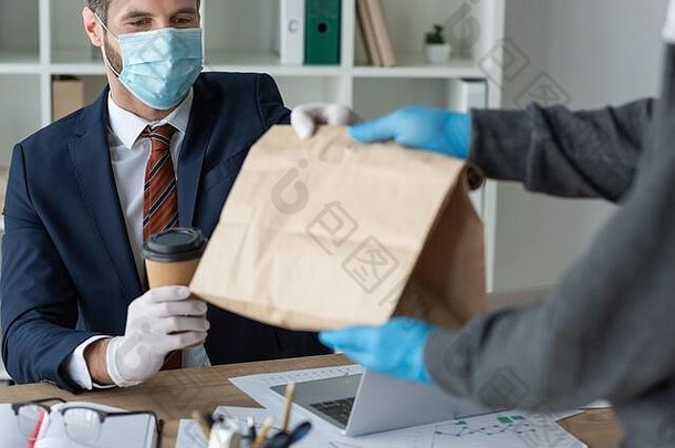 裁剪视图食物交付男人。给纸袋商人医疗面具办公室