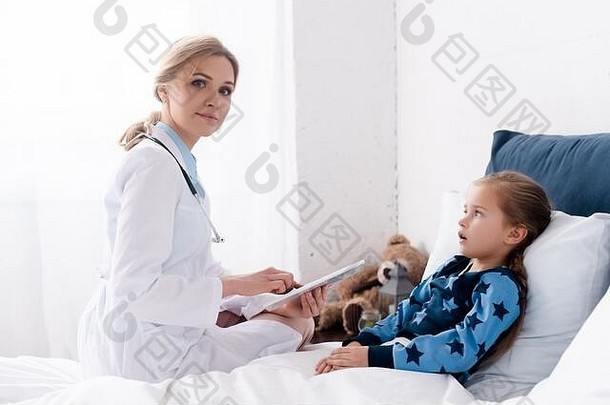 有吸引力的医生白色外套数字平板电脑生病的孩子
