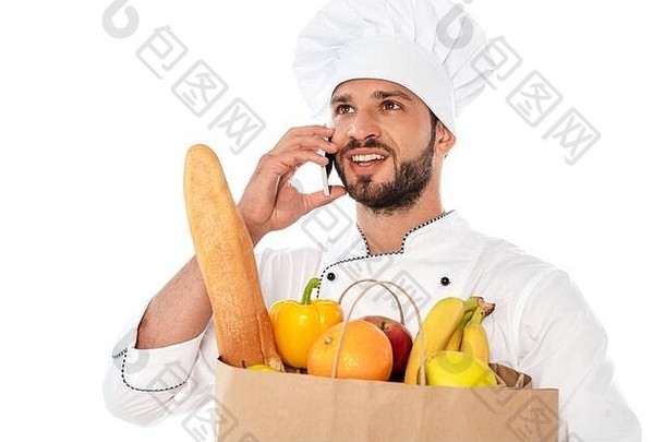 微笑烹饪会说话的智能手机持有购物袋食物孤立的白色