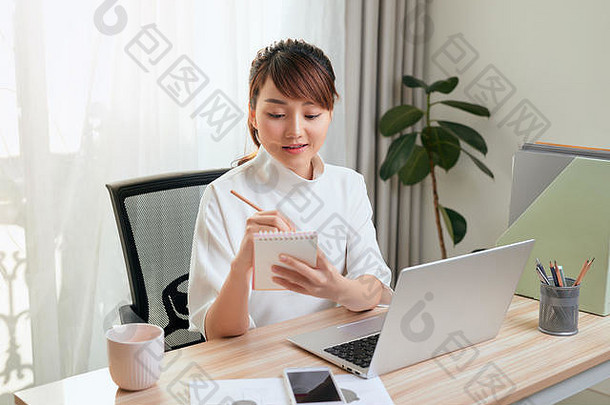 美丽的年轻的亚洲女人写作笔记本工作移动PC首页