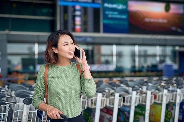 年轻的自信亚洲女人站机场移动电话