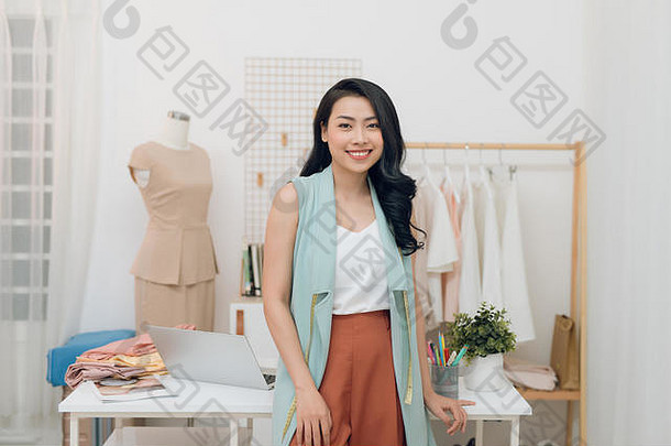年轻的亚洲时尚设计师微笑站前面桌子上车间