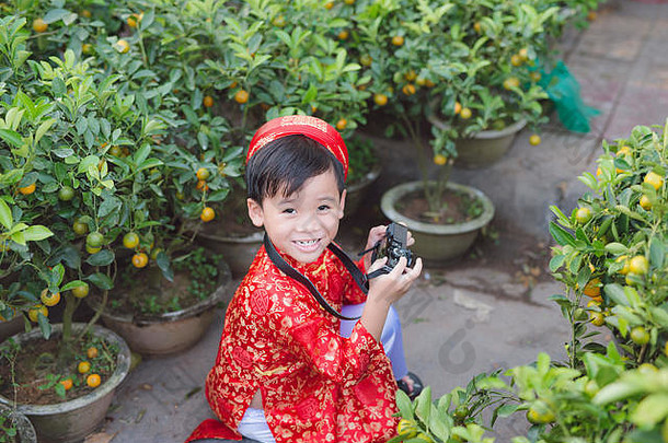 孩子数字紧凑的相机在户外可爱的越南男孩戴曼菊衣服微笑泰特假期