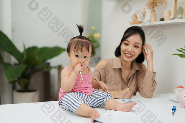 助理婴儿女孩笔坐着办公室桌子上妈妈。办公室
