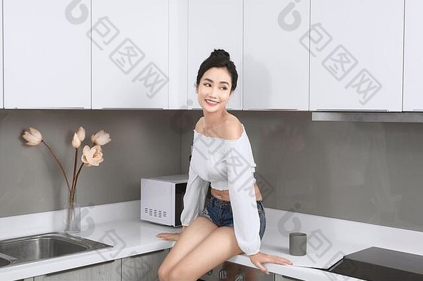 肖像快乐的女人坐在工作台面白色现代厨房