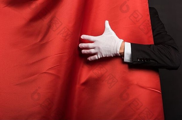 裁剪视图魔术师手套触碰红色的窗帘