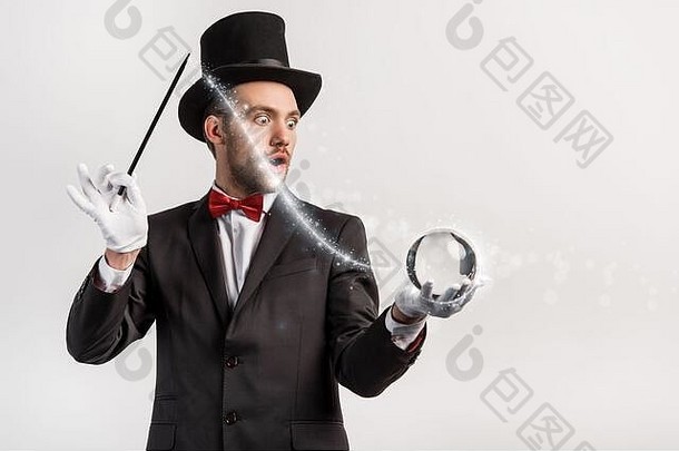震惊了魔术师持有魔杖魔法球孤立的灰色发光的插图