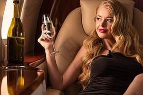 美丽的金发女郎女人香槟坐着飞机