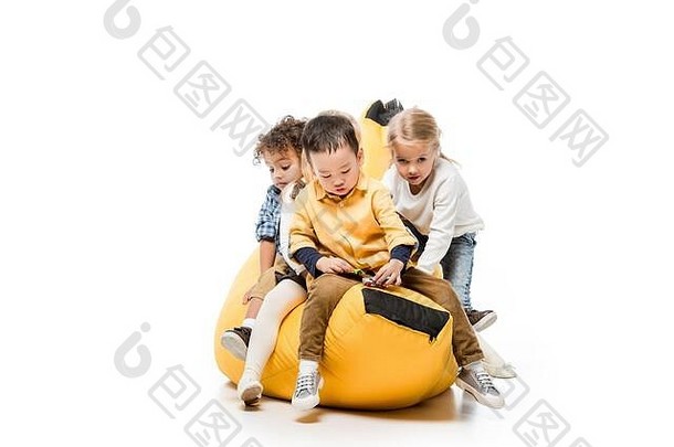 有趣的多元文化的孩子们坐着本袋椅子白色