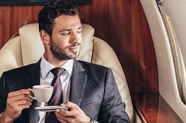 全景拍摄英俊的商人西装持有杯咖啡<strong>私人</strong>飞机