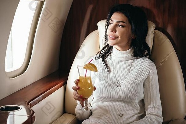 快乐女人持有美味的鸡尾酒私人飞机