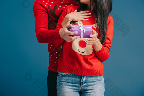 裁剪视图夫妇圣诞节毛衣持<strong>有惊喜</strong>现在孤立的蓝色的