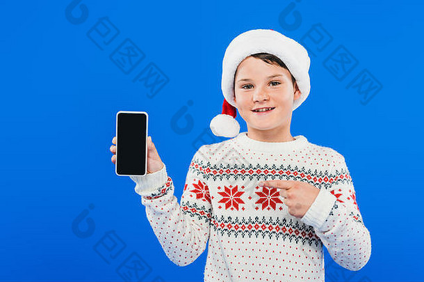 前面视图微笑孩子圣诞老人他指出手指智能手机空白屏幕孤立的蓝色的