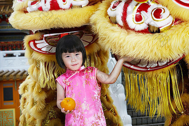 女孩持有普通话橙子摆姿势前面狮子舞者