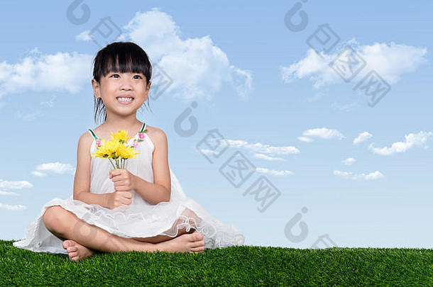 亚洲中国人女孩坐着草持有花户外公园