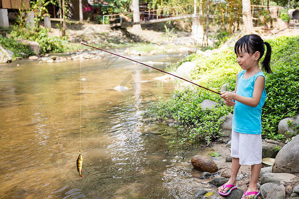 快乐亚洲中国人女孩钓鱼钓鱼杆河海岸