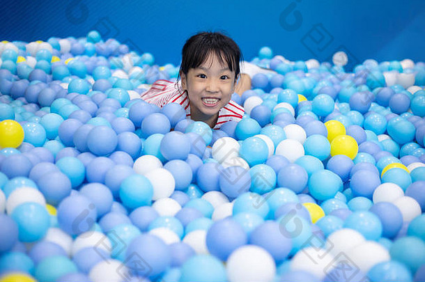 亚洲中国人女孩玩球池室内操场上