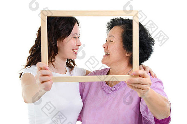 肖像亚洲高级妈妈。成人女儿手持有空照片框架孤立的白色背景