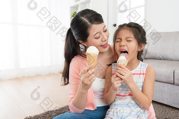微笑漂亮的女人可爱的女儿舔冰奶油感觉很酷的显示享受表达式夏天