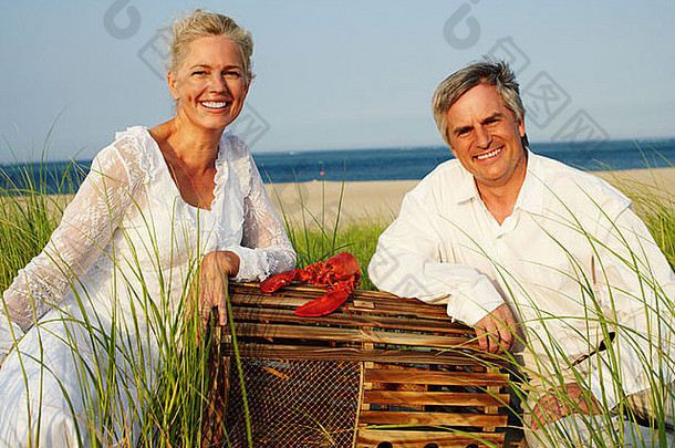 肖像成熟的夫妇坐着海滩龙虾