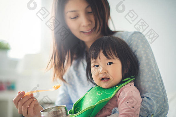 漂亮的日本女人喂养婴儿女儿勺子