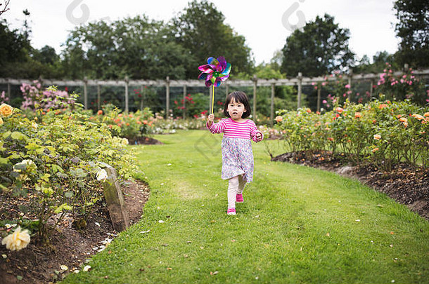 蹒跚学步的女孩玩纸风车夏天森林公园