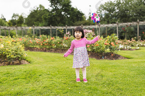 蹒跚学步的女孩玩纸风车夏天森林公园