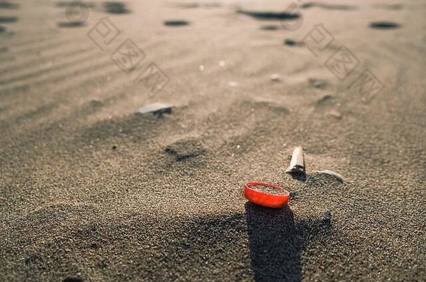 红色的塑料瓶软木塞桑迪海海岸被污染的生态系统塑料微粒