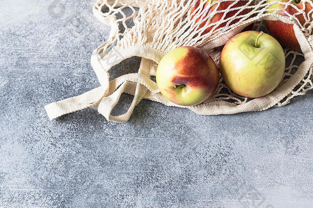 环保米色购物袋红色的苹果灰色的背景字符串袋水果浪费塑料概念
