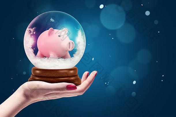 女手持有圣诞节雪全球小猪银行内部黑暗蓝色的背景