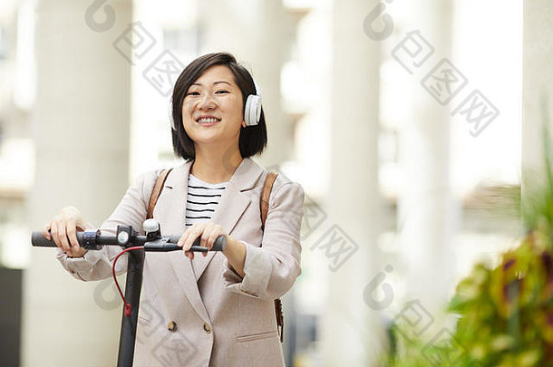 腰肖像成人亚洲女人骑电踏板车微笑幸福的相机城市街复制空间