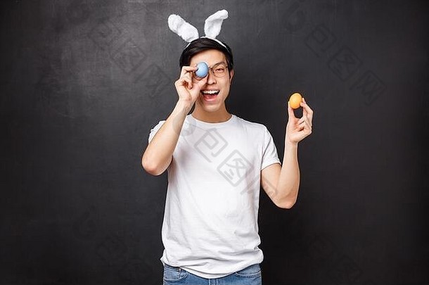 假期聚会，派对复活节概念逗乐可爱的亚洲愚蠢的的家伙兔子耳朵眼镜简单的t恤持有画鸡蛋眨眼隐藏