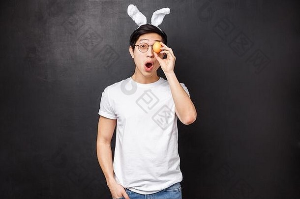 假期聚会，派对复活节概念肖像兴奋好玩的有趣的亚洲年轻的男人。兔子耳朵持有画蛋眼睛