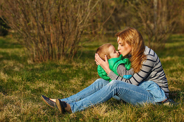 妈妈儿子坐着拥抱草坪上秋天公园家庭时间幸福童年母亲
