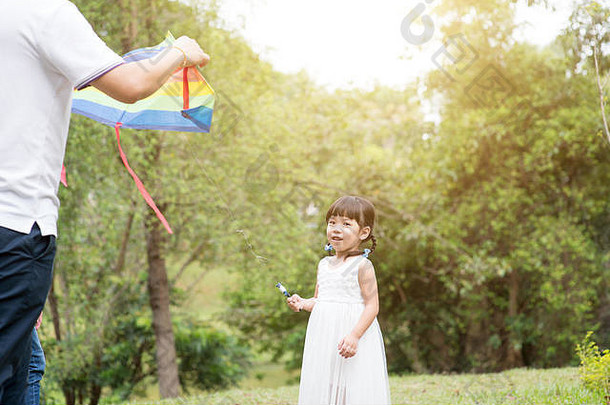 亚洲<strong>家</strong>庭在户外活动父亲女儿飞行风筝花园公园