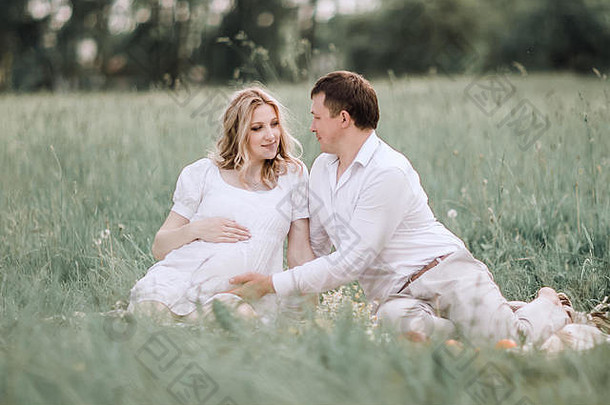美丽的怀孕了女人丈夫坐着草坪上夏天一天