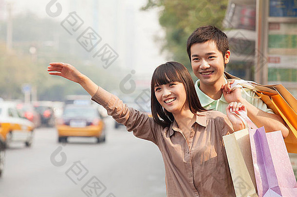 年轻的夫妇购物袋称赞出租车北京