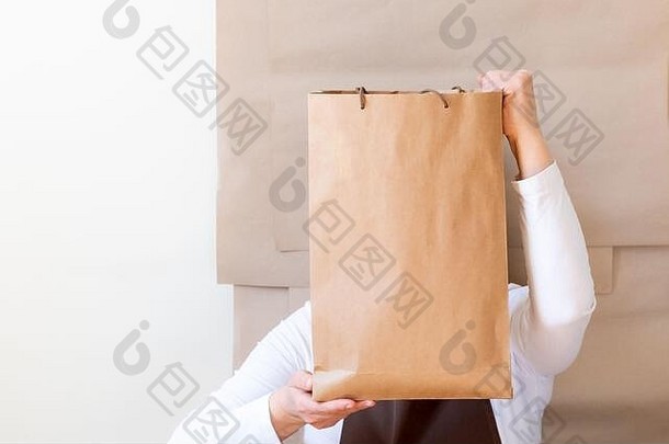 封隔器的手持有工艺纸袋盒子工人穿着棕色（的）围裙包装订单客户