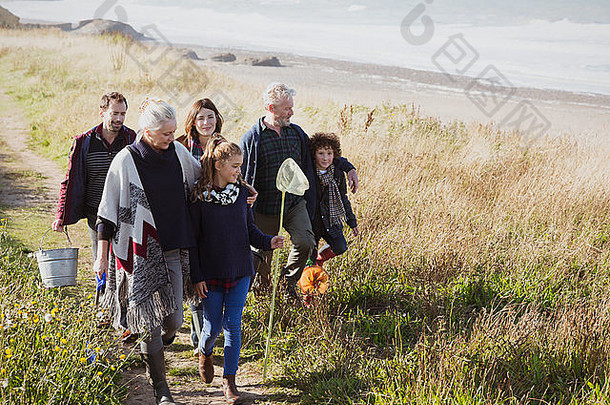 multi-generation家庭走网桶阳光明媚的草海滩路径