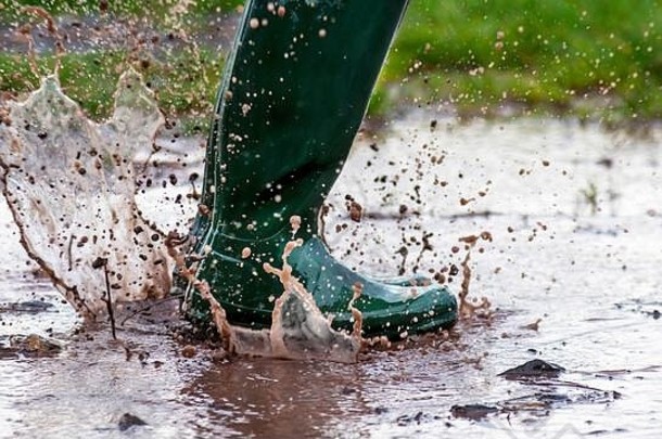 孩子跳湿泥泞的水坑绿色惠灵顿靴子早期早....光复制空间一边图像