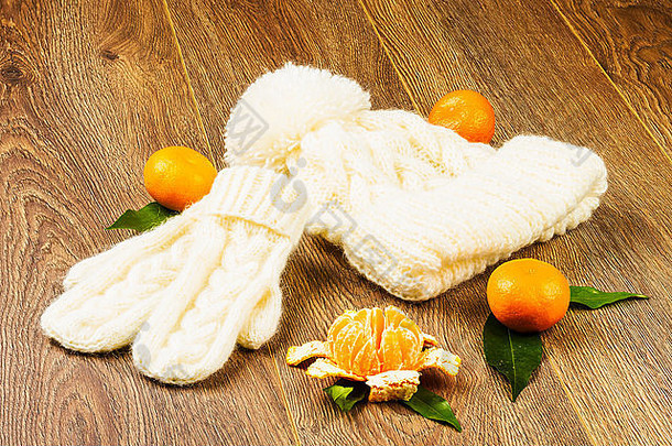 白色针织帽连指手套橘子木背景