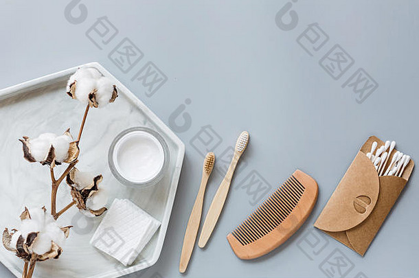 自然浴室配件木梳子竹子牙刷面部奶油耳朵棒棉花花灰色的纸背景浪费产品