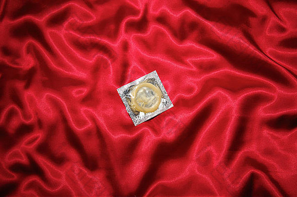 未使用的打包避孕套皱巴巴的红色的天鹅绒表