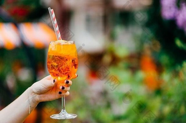 拍摄女手修指甲持有新鲜的夏天喝酒玻璃橙色冷鸡尾酒冰喝模糊背景