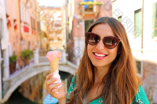 快乐美丽的女人太阳镜持有意式冰激凌冰奶油手微笑相机威尼斯桥背景威尼斯意大利