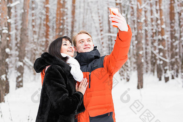 夫妇采取肖像聪明的电话冬天公园美丽的年轻的夫妇自拍