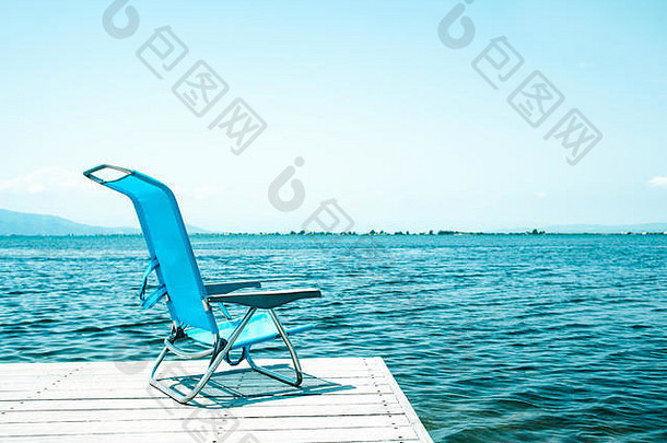 孤独的蓝色的甲板椅子结束饱经风霜的木码头水放松环境空白空间清晰的天空