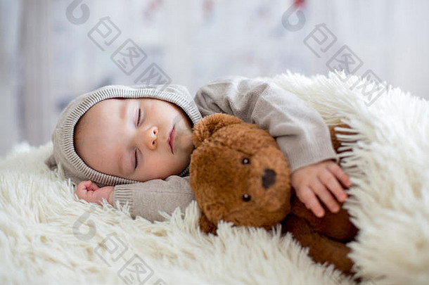 甜蜜的婴儿男孩熊睡觉床上泰迪熊塞玩具冬天景观