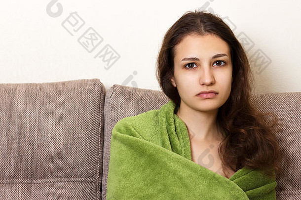 年轻的担心抑郁女人坐着沙发毯子肩膀