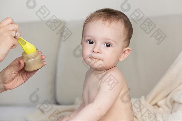 肖像可爱的婴儿男孩吃水果粥勺子